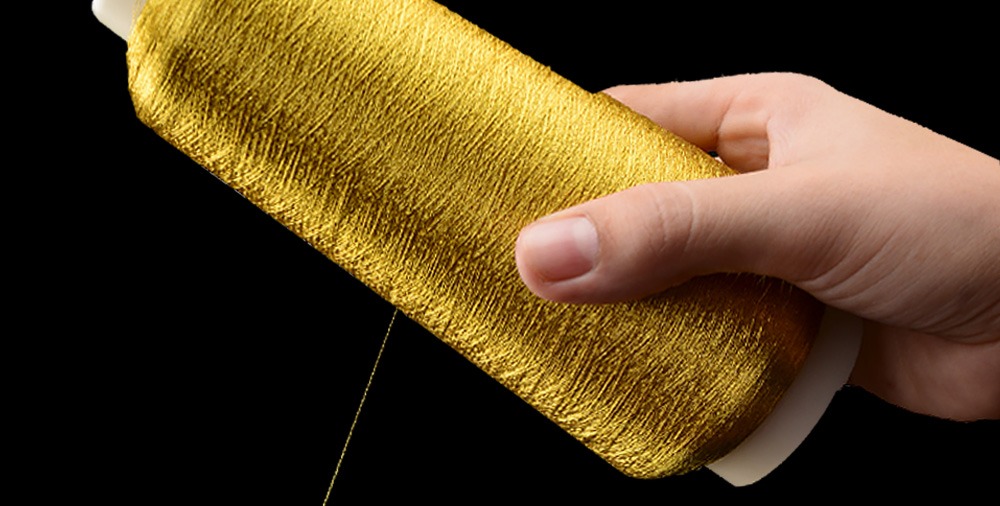 hand with bright gold metallic yarn cone